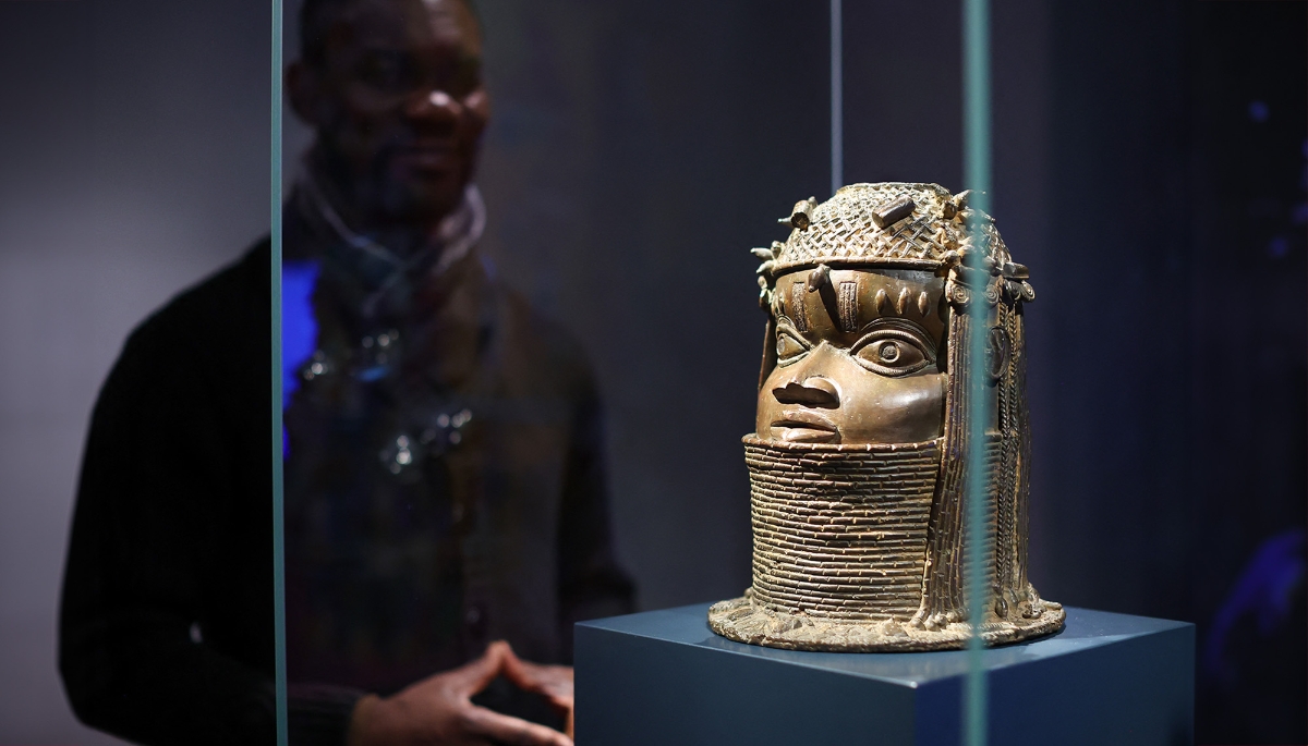 Nigerian artist Enotie Paul Ogbebor next to a Benin bronze at the Grassi Museum, Leipzig, Germany.